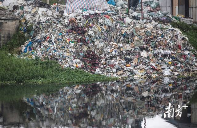 2015年，揭阳普宁市占陇镇，居民在河边的垃圾山上倾倒垃圾。