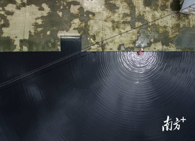 2015年，汕头潮阳区和平镇，一名妇女在墨色水塘中刷桶。